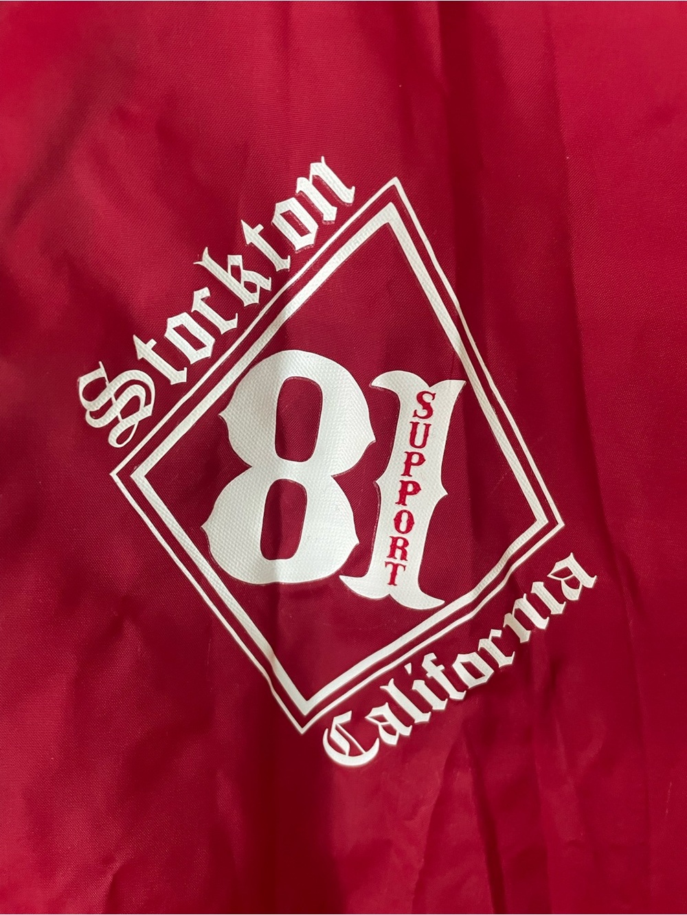 Red Lightweight Coach Rain Jacket with Stockton Support 81" logo on the chest.